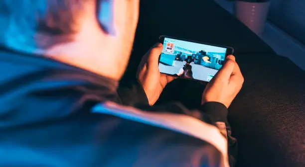 Photo of Action video game played by man holding mobile phone