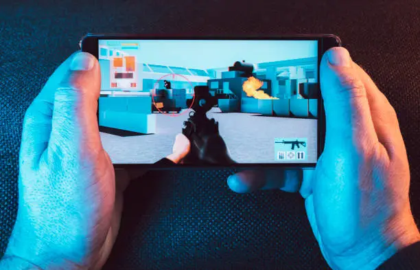 Photo of Man holds on to his smart phone as he plays a video game