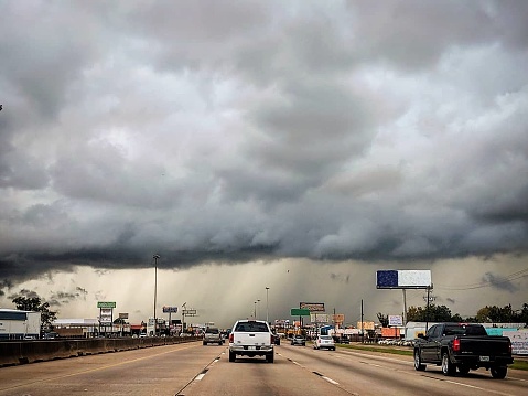 A huge, scary storm sits over Interstate 45 as cars and trucks drive into it.