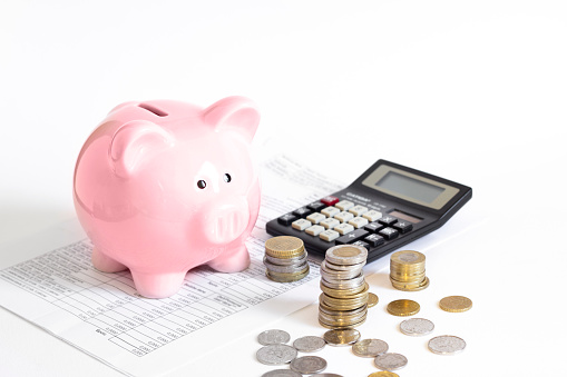 piggy bank with coins and calculator isolated on white background