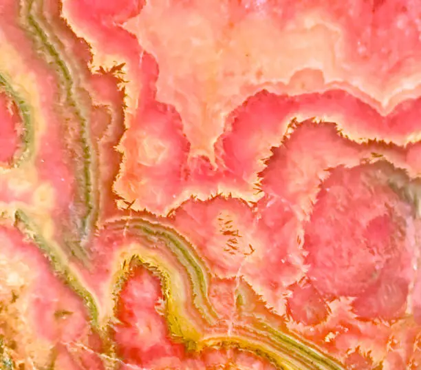 Backlit slab of pink banded rhodochrosite mineral.