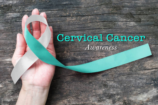 sensibilisation au cancer du col utérin avec teal et blanc ruban couleur de proue symbolique sur la femme aidant main appuyer sur le vieux bois âgés - cancer cervical photos et images de collection