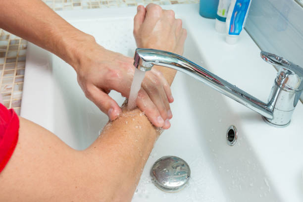 A man washes his hands up to the elbows under the tap stock photo