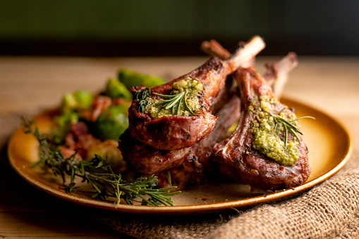 Charcoal grilled rack of lamb chops topped with pesto and rosemary and sauteed Brussel sprouts with bacon and onion p