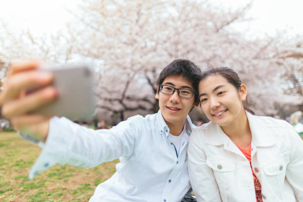 istock Couple taking selfie in front of sakura tree 1093453508