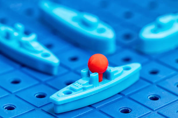 Toy war ships and submarine are placed on the playing Board in the game battleship