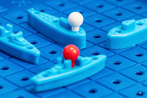 Toy war ships and submarine are placed on the playing Board in the game battleship