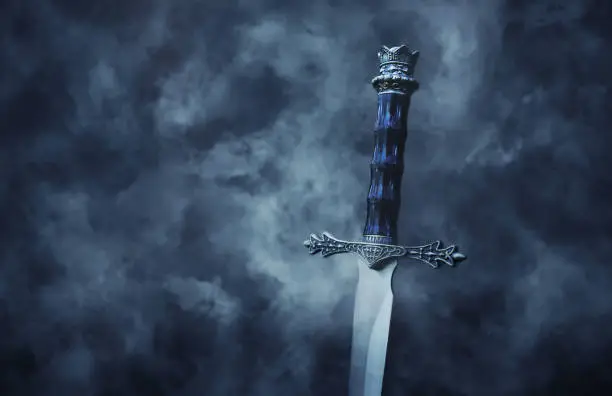 mysteriousand magical photo of silver sword over gothic snowy black background. Medieval period concept