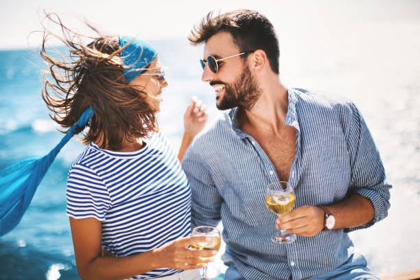 Young couple sailed into calm waters. Young couple drinking white wine on the yacht and enjoying sailing. couple drinking stock pictures, royalty-free photos & images