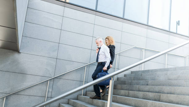 istock Business Couple Walking Down the Stairs 1093480284