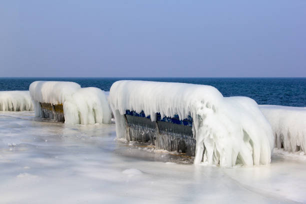 Frozen benches covered with ice at the lake side in a severe winter