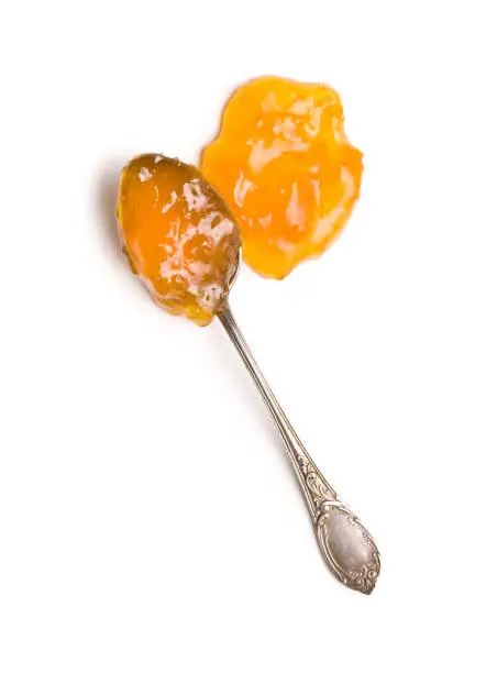 Tasty apricot jam in spoon isolated on white background. Top view.