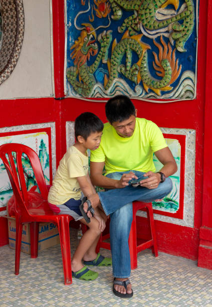 padre con hijo pequeño sentado delante de un templo chino en malacca, malasia - traditional culture dragon old asian culture fotografías e imágenes de stock