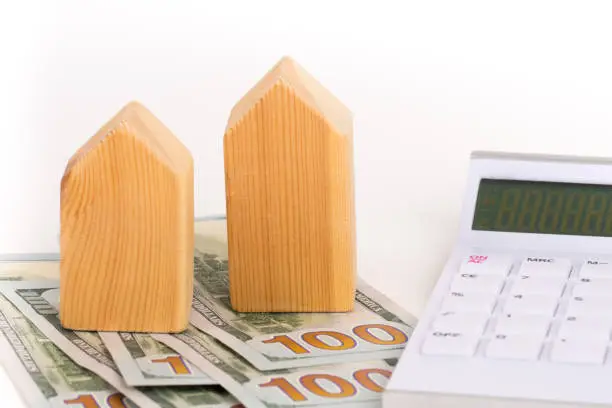 wooden house model with dollars banknotes, increase tax concept