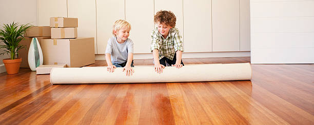 bambini unrolling tappeto in una nuova casa - unrolling foto e immagini stock