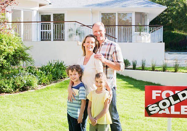 Family standing in front yard of new house next to sold sign  for sale sign photos stock pictures, royalty-free photos & images
