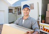Smiling man carrying box from moving van
