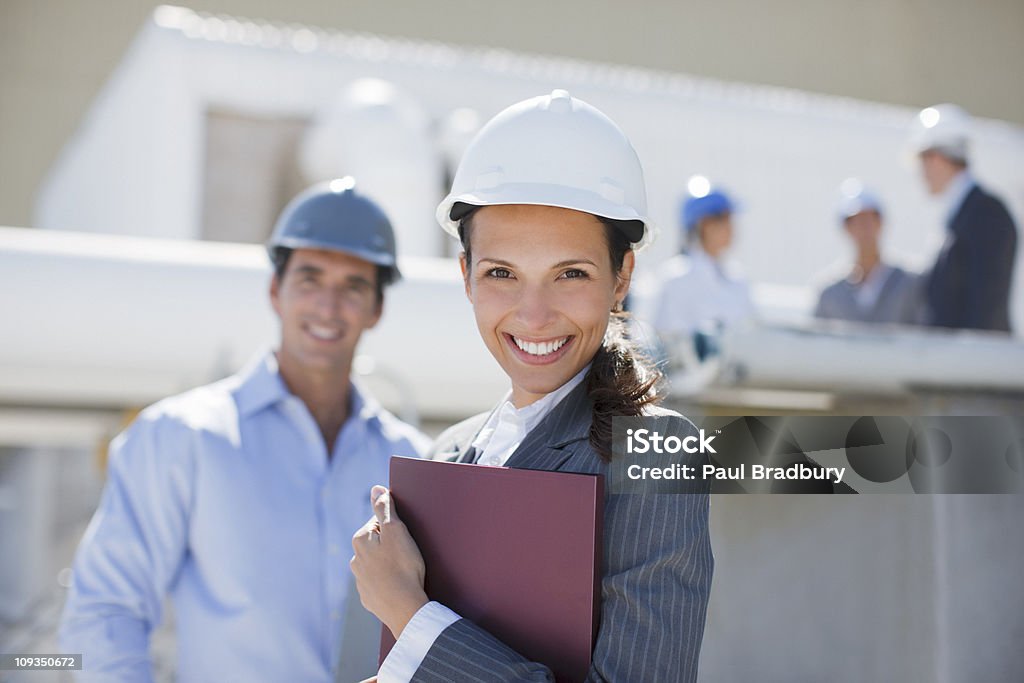 Donna d'affari in Cappello duro holding legante all'aperto - Foto stock royalty-free di Elmetto