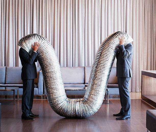 businessmen with their heads inside metal tubing - bizar stockfoto's en -beelden