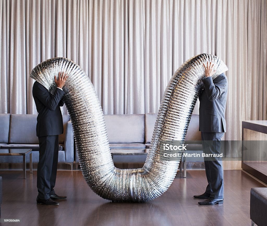 Businessmen with their heads inside metal tubing  Bizarre Stock Photo