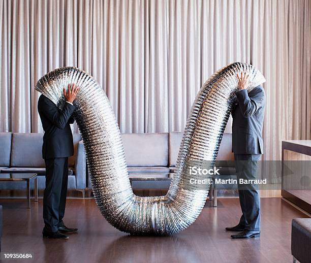 Businessmen With Their Heads Inside Metal Tubing Stock Photo - Download Image Now - Bizarre, Humor, Communication