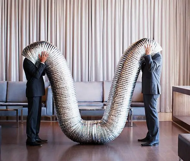 Photo of Businessmen with their heads inside metal tubing