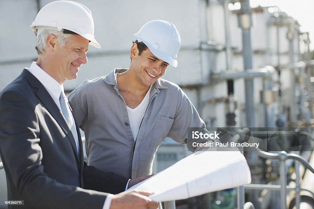 Uomo d'affari e assistente esaminando progetto all'aperto - Foto stock royalty-free di Cantiere di costruzione
