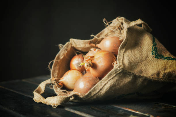 istock hand hold fresh onion cloth bag isolated on wooden surface b 1093507438