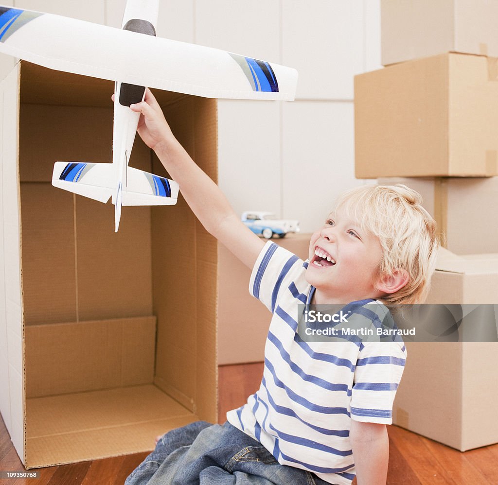 Sorridente Menino brincando com modelo de avião em sua nova casa - Foto de stock de Brinquedo royalty-free