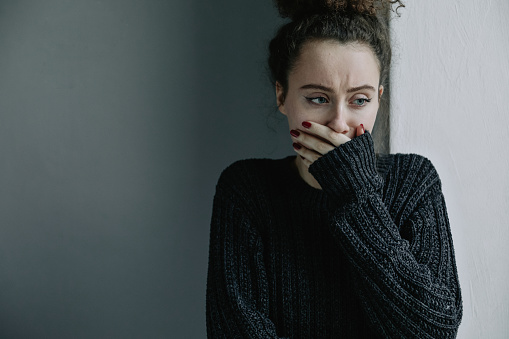 Cerca de adolescente con depresión y bulimia sentado solo en el cuarto oscuro. Ella cubre su rostro con las manos. Problemas mentales con depresión y bulimia. photo