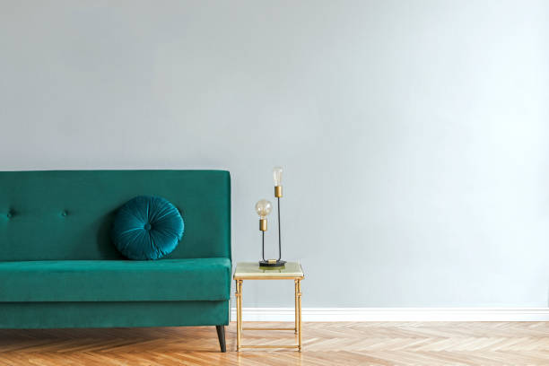 istock Minimalistic and luxury grey home interior with green velvet design sofa, gold coffe table with table lamp. Copy space for inscription, mock up poster. Empty wall. Brown wooden parquet. 1093510662