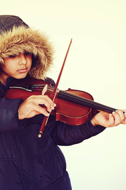 istock Bright vertical capture of a boy with lovely lips playing the stringed and bowed musical instrument, the violin 1093521416