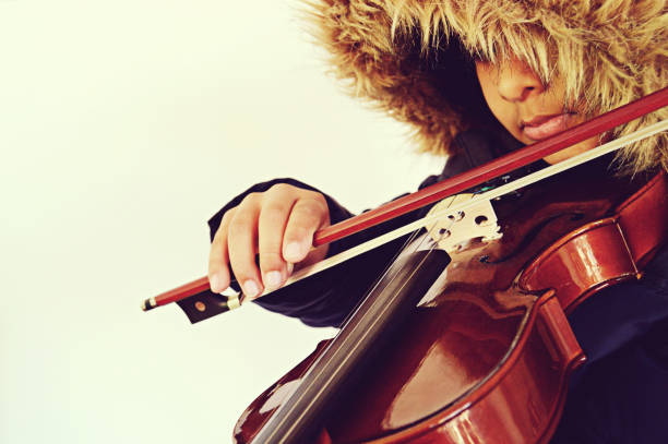 A boy playing the stringed and bowed musical instrument, the violin