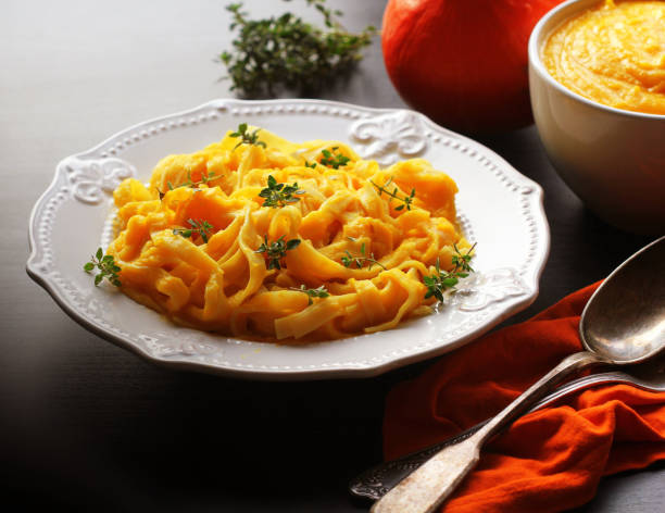 Tagliatelle pasta with pumpkin cream sauce over black background stock photo