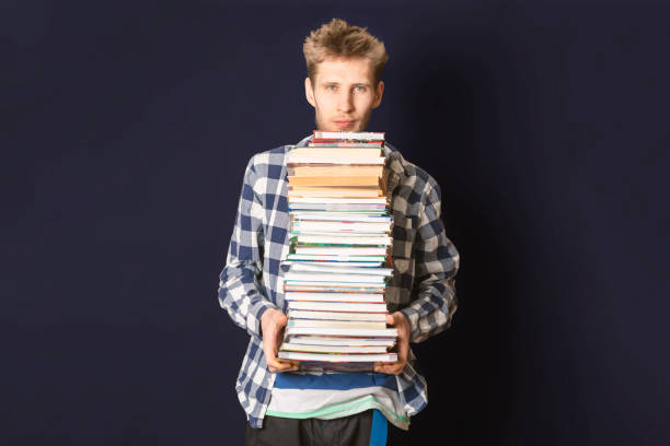istock casual student carry huge stack of books on dark background f 1093523194