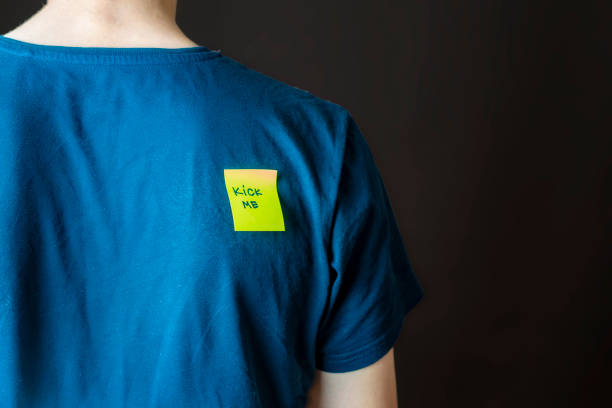 istock hand glue yellow kick me sticker on persons back at aprill fool day b 1093523204