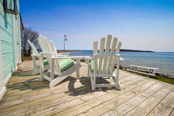 Mackinaw Island Life In Michigan Adirondack chairs on a wooden deck with a view of Lake Huron at the Mackinaw Island Public Library. pretty beach house stock pictures, royalty-free photos & images