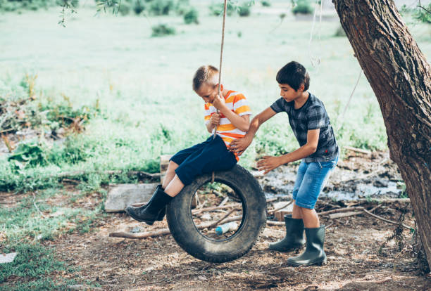 little boys swinging on a tire - freedom tire swing tire swing imagens e fotografias de stock