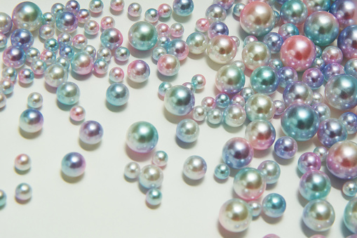 Vertical texture of round pearl beads of different sizes on a light background