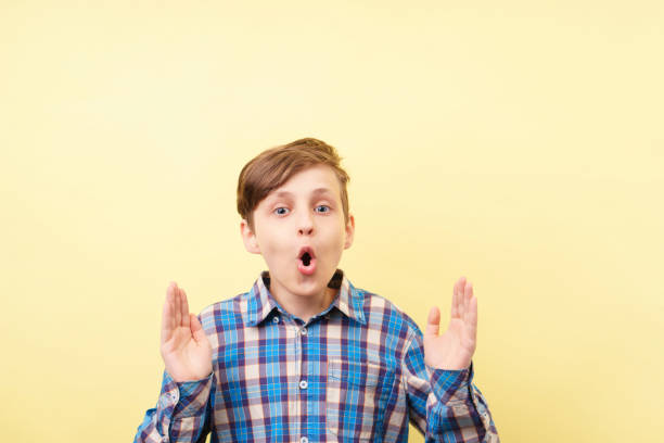 istock astounded boy with open mouth at yellow background 1093531956