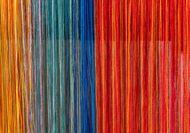 Colored threads of an ancient wooden loom .