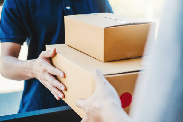 Asian Man hand accepting a delivery boxes from professional deliveryman at home stock photo