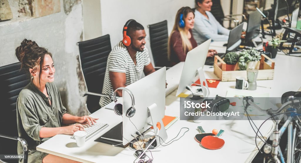 Young trendy teamwork using computer in creative coworking office - Business people working together at new app project - Focus on left woman face - Technology, influencer, marketing and job concept Technology Stock Photo