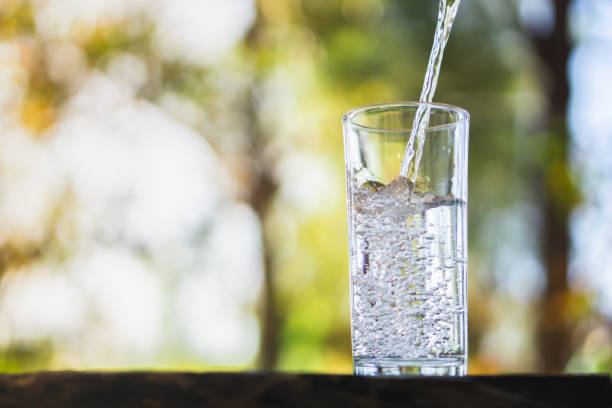 istock Pouring fresh water on drinking glass over nature background 1093567250