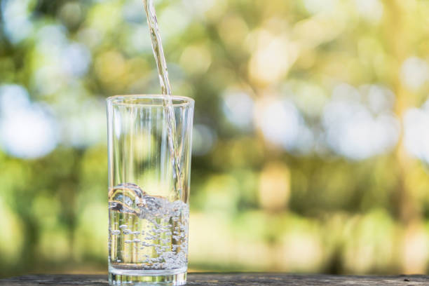 istock Pouring fresh water on drinking glass over nature background 1093567354