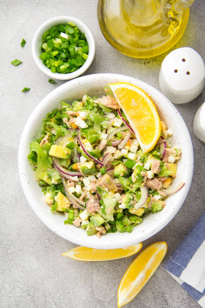 istock Salad with tuna, avocado, onion, egg and lemon. Spring healthy delicious lunch on light background 1093570068