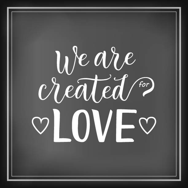 istock Modern calligraphy lettering of We are created for love in white on chalkboard background decorated with hearts and frame 1093572986