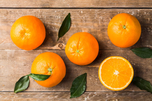 vue de dessus de composition de fruits oranges avec des feuilles vertes et tranche sur la table en bois - isolated on white orange juice ripe leaf photos et images de collection