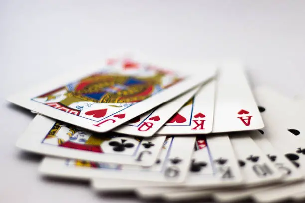 Photo of Playing Cards fanned out: Suit of Spades, Clubs and Diamonds fanned out over white background. Gambling, Poker, Win, Lose, Chance, Gambling, Money, Red, Black, Jack, Queen, King