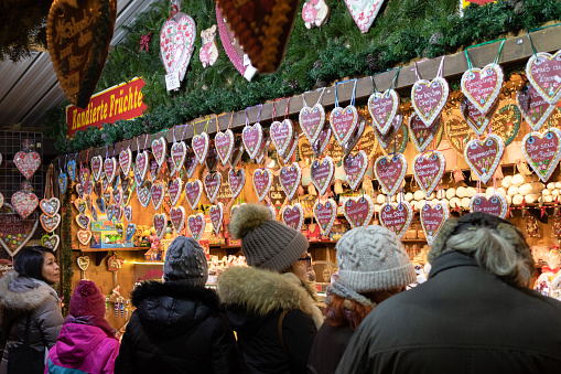 Vienna, December 14, 2018: People at Christmas market in Vienna selecting traditional sweet souvenir - decorated heart shape gingerbreads